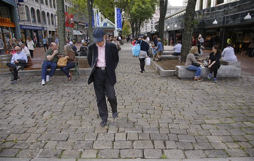 A man walks along the cobblestone promenade at the Quincy Market Tuesday, Oct. 7, 2014 in Boston. The owners of Boston's historic Quincy Market are envisioning a major overhaul of the iconic complex of food vendors and retailers. (AP Photo/Stephan Savoia)